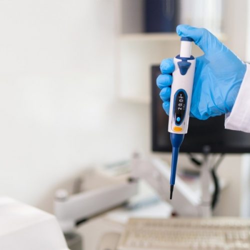 Paracoccidioidomicose laboratory technician holding a pipette tool in his hand in a blue picture id1277027038