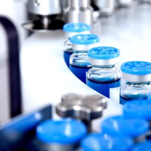 Garrafas de vidro em produção na bandeja de um distribuidor líquido automático, uma linha para encher medicamentos contra bactérias e vírus, antibióticos e vacina