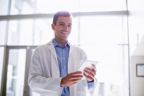 Portrait of smiling doctor using digital tablet in hospital corridor